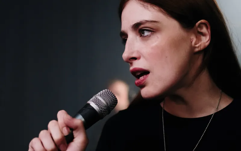 Cantora se apresentando com um microfone em um estúdio.